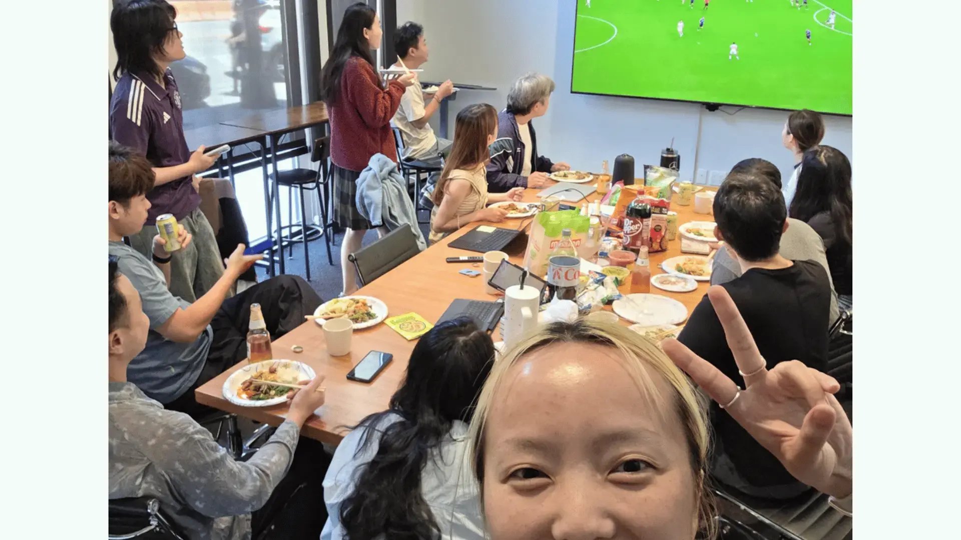GoElite team members are sharing a meal and watching the World Cup together during an office gathering.