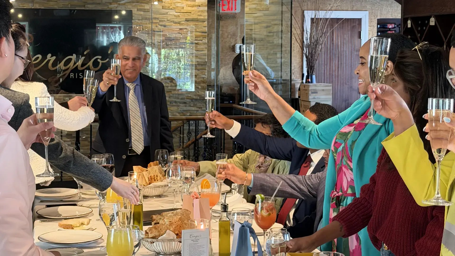 Guests raising champagne glasses during a GoElite and Monroe networking dinner celebration.